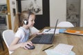 Beautiful young girl with headset is sitting in front of her laptop during corona time and is having video call Royalty Free Stock Photo