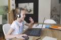 Beautiful young girl with headset is sitting in front of her laptop during corona time and is having video call Royalty Free Stock Photo