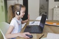 Beautiful young girl with headset is sitting in front of her laptop during corona time and is having video call Royalty Free Stock Photo