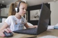 Beautiful young girl with headset is sitting in front of her laptop during corona time and is having video call Royalty Free Stock Photo