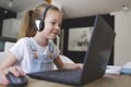 Beautiful young girl with headset is sitting in front of her laptop during corona time and is having video call Royalty Free Stock Photo