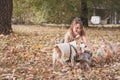 Beautiful young girl with her dog puppy enjoying in the autumn day in the park selective focus Royalty Free Stock Photo