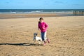 Portrait of a beautiful young girl and her puppy running on the beach