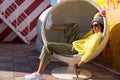 Beautiful young girl in hipster clothes , sunglasses , hat resting in a round chair Royalty Free Stock Photo