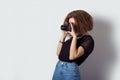 Beautiful young girl hipster makes the images, photographs on the camera in jeans and a black t-shirt in the Studio