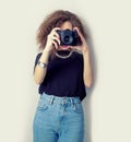 Beautiful young girl hipster makes the images, photographs on the camera in jeans and a black t-shirt in the Studio