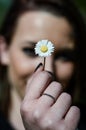 Beautiful young girl holding a daisy flower in a spring sunny day.