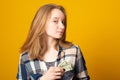 Beautiful young girl is holding dollars in her shirt pocket. Happy teen girl with money Royalty Free Stock Photo