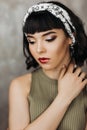 A beautiful young girl with a hoop on her head, a brunette with a short haircut, red lips. Beauty fashion portrait.