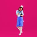 Beautiful young girl in image of retro cater waiter wearing 70s, 80s fashion style uniform isolated over bright pink Royalty Free Stock Photo
