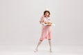 Beautiful young girl in image of retro cater waiter wearing 70s, 80s fashion style uniform isolated over light studio Royalty Free Stock Photo