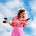 Beautiful young girl in image of retro cater waiter wearing 70s, 80s fashion style uniform shouting into phone over sky Royalty Free Stock Photo