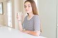 Beautiful young girl kid drinking a fresh glass of water with a confident expression on smart face thinking serious Royalty Free Stock Photo