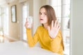 Beautiful young girl kid drinking a fresh glass of water with open hand doing stop sign with serious and confident expression, Royalty Free Stock Photo