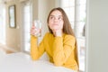 Beautiful young girl kid drinking a fresh glass of water serious face thinking about question, very confused idea Royalty Free Stock Photo