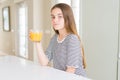 Beautiful young girl kid drinking a glass of fresh orange juice with a confident expression on smart face thinking serious Royalty Free Stock Photo