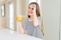 Beautiful young girl kid drinking a glass of fresh orange juice with happy face smiling doing ok sign with hand on eye looking Royalty Free Stock Photo