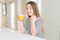 Beautiful young girl kid drinking a glass of fresh orange juice pointing and showing with thumb up to the side with happy face Royalty Free Stock Photo