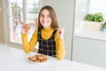 Beautiful young girl kid eating chocolate chips cookies very happy pointing with hand and finger to the side Royalty Free Stock Photo