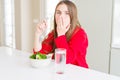 Beautiful young girl kid eating fresh broccoli and drinking water cover mouth with hand shocked with shame for mistake, expression Royalty Free Stock Photo