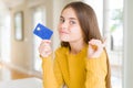 Beautiful young girl kid holding credit card very happy pointing with hand and finger to the side Royalty Free Stock Photo