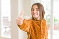 Beautiful young girl kid at home doing happy thumbs up gesture with hand Royalty Free Stock Photo