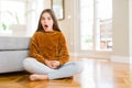 Beautiful young girl kid sitting on the floor at home afraid and shocked with surprise expression, fear and excited face Royalty Free Stock Photo