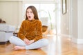 Beautiful young girl kid sitting on the floor at home afraid and shocked with surprise expression, fear and excited face Royalty Free Stock Photo