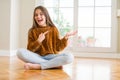 Beautiful young girl kid sitting on the floor at home amazed and smiling to the camera while presenting with hand and pointing Royalty Free Stock Photo