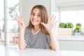 Beautiful young girl kid wearing stripes t-shirt showing and pointing up with fingers number eight while smiling confident and