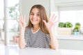 Beautiful young girl kid wearing stripes t-shirt showing and pointing up with fingers number nine while smiling confident and