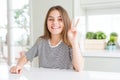 Beautiful young girl kid wearing stripes t-shirt showing and pointing up with fingers number two while smiling confident and happy