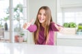 Beautiful young girl kid on white table approving doing positive gesture with hand, thumbs up smiling and happy for success Royalty Free Stock Photo