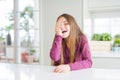 Beautiful young girl kid on white table covering one eye with hand with confident smile on face and surprise emotion Royalty Free Stock Photo