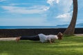 Beautiful young girl in leggings and tunic makes yoga practice, meditation, low plank asana on the ocean beach Bali Indonesia Royalty Free Stock Photo