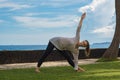 Beautiful young girl in leggings and tunic makes yoga practice, meditation, stretching asana on the ocean beach Bali Indonesia Royalty Free Stock Photo