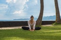 Beautiful young girl in leggings and tunic makes yoga practice, meditation, stretching asana on the ocean beach in Bali Indonesia Royalty Free Stock Photo