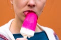 Beautiful and young girl licks cold red ice cream tongue