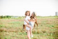 A beautiful young girl, with light curly hair in a straw hat with a little sister hugging and laughing near horses Royalty Free Stock Photo