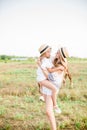 A beautiful young girl, with light curly hair in a straw hat with a little sister hugging and laughing near horses Royalty Free Stock Photo