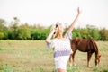 A beautiful young girl, with light curly hair in a straw hat near horses, in the countryside, warm autumn Royalty Free Stock Photo