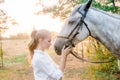 Beautiful young girl with light hair in uniform competition hugs her horse : outdoors portrait on sunny day on sunset Royalty Free Stock Photo