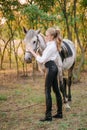 Beautiful young girl with light hair in uniform competition hugs her horse : outdoors portrait on sunny day on sunset Royalty Free Stock Photo