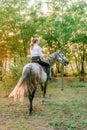 Beautiful young girl with light hair in uniform competition smiling and astride a horse in sunset