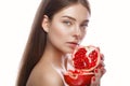 Beautiful young girl with a light natural make-up and perfect skin with pomegranate in her hand . Beauty face. Royalty Free Stock Photo