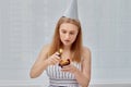 A beautiful young girl lights a festive cupcake for her birthday.