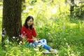 Beautiful young girl Listen to music on a mobile phone while sitting under giant oak