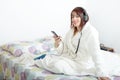 Beautiful young girl listening to music in her bed Royalty Free Stock Photo