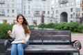 A beautiful young girl with long brown hair sitting on the bench with the book and eyeglasses in his hands. She left the house in