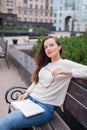 A beautiful young girl with long brown hair sitting on the bench with the book and eyeglasses in his hands. She left the house in